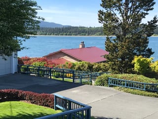 Single-story ranch home with Interlock Tile Red aluminum slate metal roof and chimney, set on a waterfront hillside in Anacortes, WA.