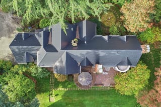 Black Interlock Slate aluminum roof on a two-storey home with a slate roof and dormers among tall, Seattle, Washington