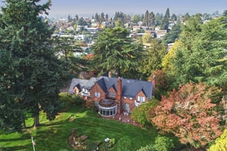 Black Interlock Slate aluminum roof on a red brick house with a black metal roof among tall trees, Seattle, Washington