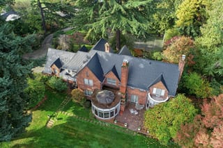 Black Interlock Slate aluminum roof on a brick two-storey Colonial home among tall trees in an, Seattle, Washington