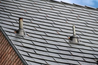 Black Interlock Slate aluminum roof on a grey two-storey home with dormers in a urban setting, Seattle, Washington