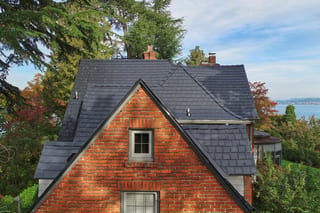 Black Interlock Slate aluminum roof on a red brick two-storey craftsman home with dormers among, Seattle, Washington