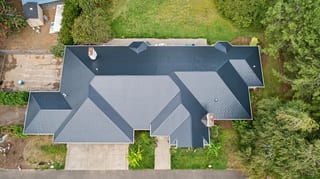 Black Interlock Slate aluminum roof on a modern home with a black metal roof in a wooded area, Ridgefield, Washington