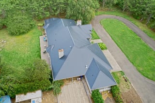 Black Interlock Slate aluminum roof on a black ranch style home in a forested rural setting, Ridgefield, Washington
