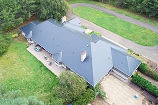 Black Interlock Slate aluminum roof on a black single-family home with two storeys in a forested, Ridgefield, Washington