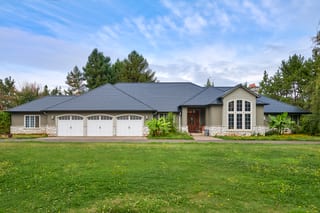 Front elevation of a single-story Craftsman home in Ridgefield, WA with a complex hip Interlock black aluminum slate metal roof and stone accents.