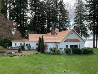 Copper Penny Interlock Shake aluminum roof on a white cottage among tall evergreens on the water, Bremerton, Washington