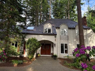 Colonial Brown Interlock Shake aluminum roof on a Colonial home with a brown metal roof among tall trees, Bellingham, Washington