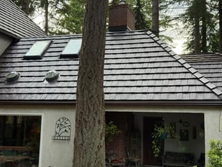 Colonial Brown Interlock Shake aluminum roof on a colonial brown metal roof on a white house among tall, Bellingham, Washington