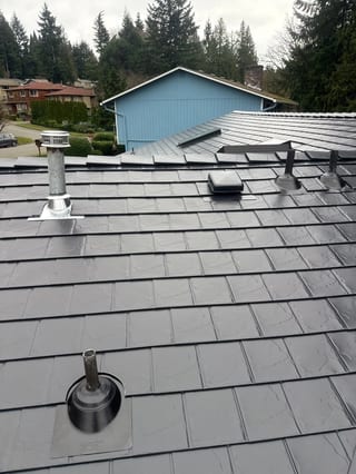 Black Interlock Slate aluminum roof on a red one-storey home with a gable and dormers in a forest, Redmond, Washington