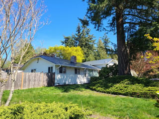 Deep Charcoal Interlock Slate aluminum roof on a white one-storey home with a metal roof in a wooded, Lynnwood, Washington