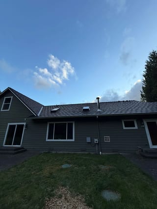 Black Interlock Shake aluminum roof on a black home with a metal roof among tall trees, Marysville, Washington