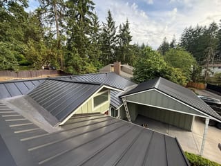 Black Interlock Standing Seam aluminum roof on a modern home with a black metal roof in a forested setting, Lakewood, Washington