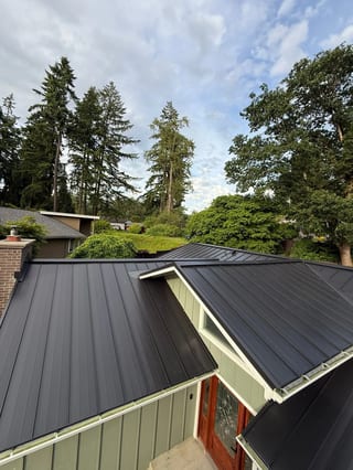 Black Interlock Standing Seam aluminum roof on a home with a black metal roof among trees in a forested, Lakewood, Washington