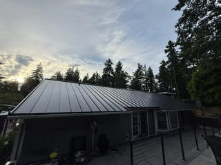 Black Interlock Standing Seam aluminum roof on a black ranch style home among tall trees, Lakewood, Washington
