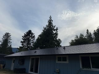 Black Interlock Cedar Shingle aluminum roof on a blue single-story ranch with a metal roof in the woods, North Bend, Washington