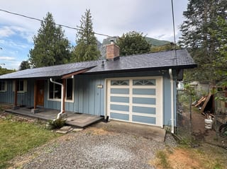 Black Interlock Cedar Shingle aluminum roof on a blue one-storey home with a metal roof in a forested, North Bend, Washington