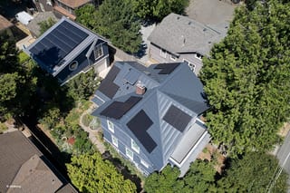Deep Charcoal Interlock Standing Seam aluminum roof on a large house with a metal roof among tall trees in an, Seattle, Washington
