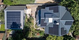 Deep Charcoal Interlock Standing Seam aluminum roof on a grey home with a metal roof among tall trees, Seattle, Washington