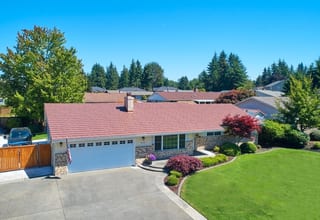 Aged Copper Interlock Shake aluminum roof on a ranch home with a red metal roof among green lawns, Puyallup, Washington