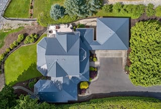 Deep Charcoal Interlock Slate aluminum roof on a house with a metal roof among green trees, Blaine, Washington