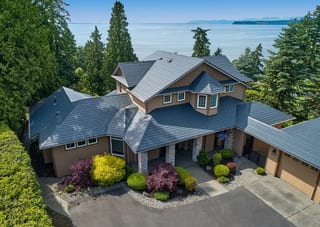 Deep Charcoal Interlock Slate aluminum roof on a tan two-storey home with dormers on waterfront, Blaine, Washington