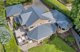 Deep Charcoal Interlock Slate aluminum roof on a tan two-storey home with dormers and a large front porch, Blaine, Washington