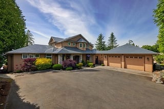 Deep Charcoal Interlock Slate aluminum roof on a brown two-storey home with dormers among tall trees, Blaine, Washington