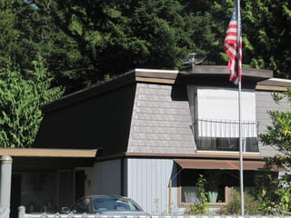 Tudor Brown Interlock Slate aluminum roof on a Tudor-style home with a metal roof in a forested suburban, Allyn, Washington