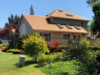Aged Copper Interlock Tile aluminum roof on a two-storey home with a tan roof and brown siding in a, Arlington, Washington