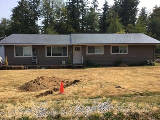Musket Grey Interlock Slate aluminum roof on a grey ranch-style home with a metal roof among evergreen, Bonney Lake, Washington