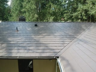 Tudor Brown Interlock Slate aluminum roof on a brown two-storey Tudor home among tall evergreens, University Place, Washington