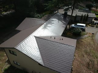 Tudor Brown Interlock Slate aluminum roof on a beige Tudor home with dormers in a forested setting, University Place, Washington
