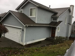 Deep Charcoal Interlock Slate aluminum roof on a grey two-storey home with dormers among tall pines, Silverdale, Washington