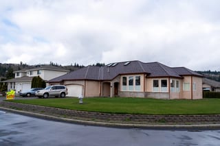Colonial Brown Interlock Shake aluminum roof on a tan home with a brown roof among green trees, Orting, Washington
