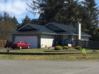 Black Interlock Slate aluminum roof on a single-storey ranch-style home with a chimney among trees, Ocean Shores, Washington