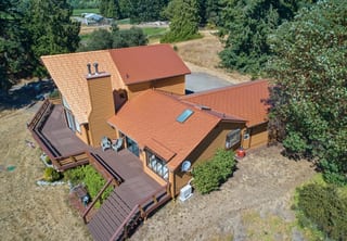 Copper Penny Interlock Cedar Shingle aluminum roof on a copper penny metal roofed chalet among tall evergreen, Sequim, Washington