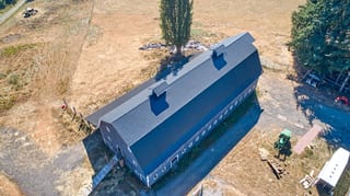 Black Interlock Slate aluminum roof on a black one-storey home with a metal roof in a rural setting, Longview, Washington