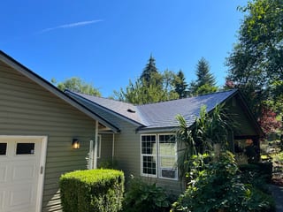 Deep Charcoal Interlock Cedar Shingle aluminum roof on a green single-storey ranch home with dormers in a forest, Longview, Washington