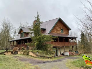 Colonial Brown Interlock Cedar Shingle aluminum roof on a colonial style home with a metal roof among tall trees, Port Angeles, Washington