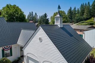 Black Interlock Slate aluminum roof on a white one-storey home with dormers among tall evergreens, Enumclaw, Washington