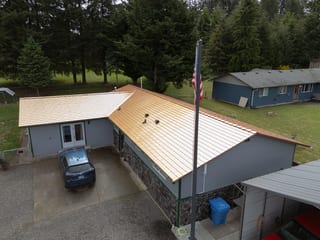 Copper Penny Interlock Slate aluminum roof on a gray ranch-style home with a metal roof in a wooded area, Castle Rock, Washington
