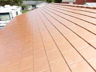 Copper Penny Interlock Slate aluminum roof on a tan single-family home with a copper penny metal roof in, Castle Rock, Washington