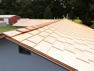 Copper Penny Interlock Slate aluminum roof on a house with a copper penny metal roof among tall evergreen, Castle Rock, Washington