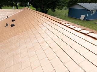 Copper Penny Interlock Slate aluminum roof on a one-storey home with a grey roof among green trees, Castle Rock, Washington