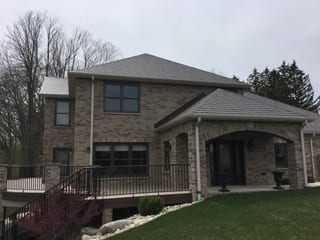 Colonial Brown Interlock Slate aluminum roof on a brown two-storey home with a metal roof and stone facade, Horicon, Wisconsin