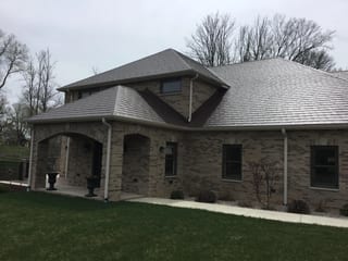 Colonial Brown Interlock Slate aluminum roof on a brown Colonial home with dormers in a wooded area, Horicon, Wisconsin