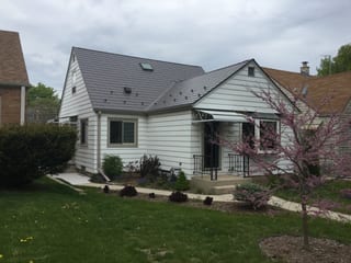 Weathered Interlock Slate aluminum roof on a white ranch home with a brown roof among trees, Milwaukee, Wisconsin