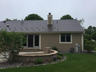 Colonial Brown Interlock Slate aluminum roof on a Colonial home with a metal roof among tall trees, Port Washington, Wisconsin