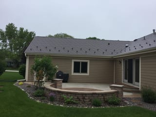 Colonial Brown Interlock Slate aluminum roof on a brown single-storey home with a metal roof among tall, Port Washington, Wisconsin